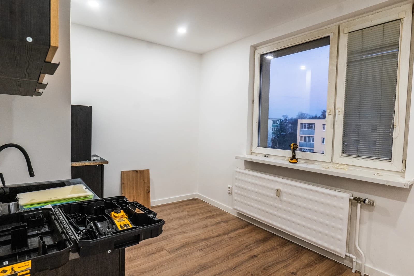 Štýlová tmavá kuchyňa s moderným osvetlením, zlatými akcentmi a elegantným jedálenským stolom.