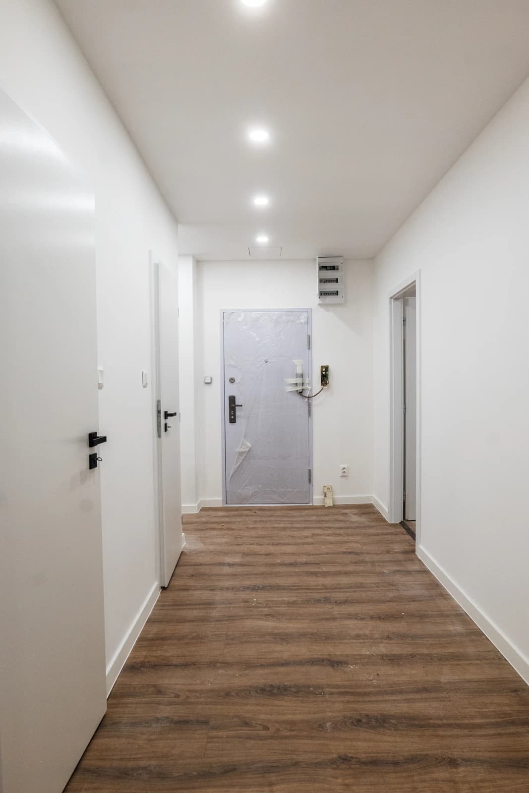 Štýlová tmavá kuchyňa s moderným osvetlením, zlatými akcentmi a elegantným jedálenským stolom.