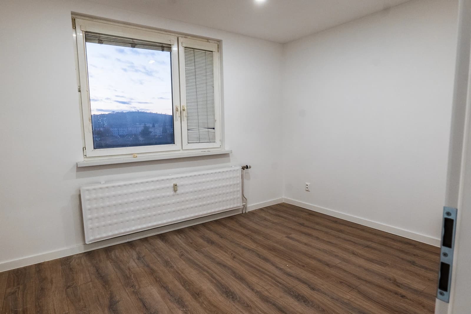 Štýlová tmavá kuchyňa s moderným osvetlením, zlatými akcentmi a elegantným jedálenským stolom.