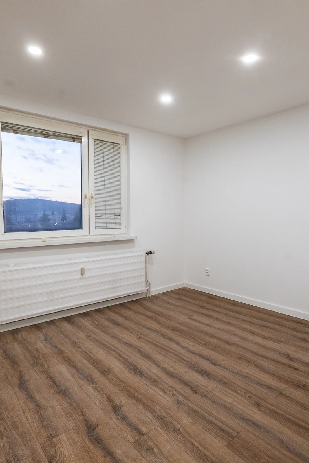 Štýlová tmavá kuchyňa s moderným osvetlením, zlatými akcentmi a elegantným jedálenským stolom.