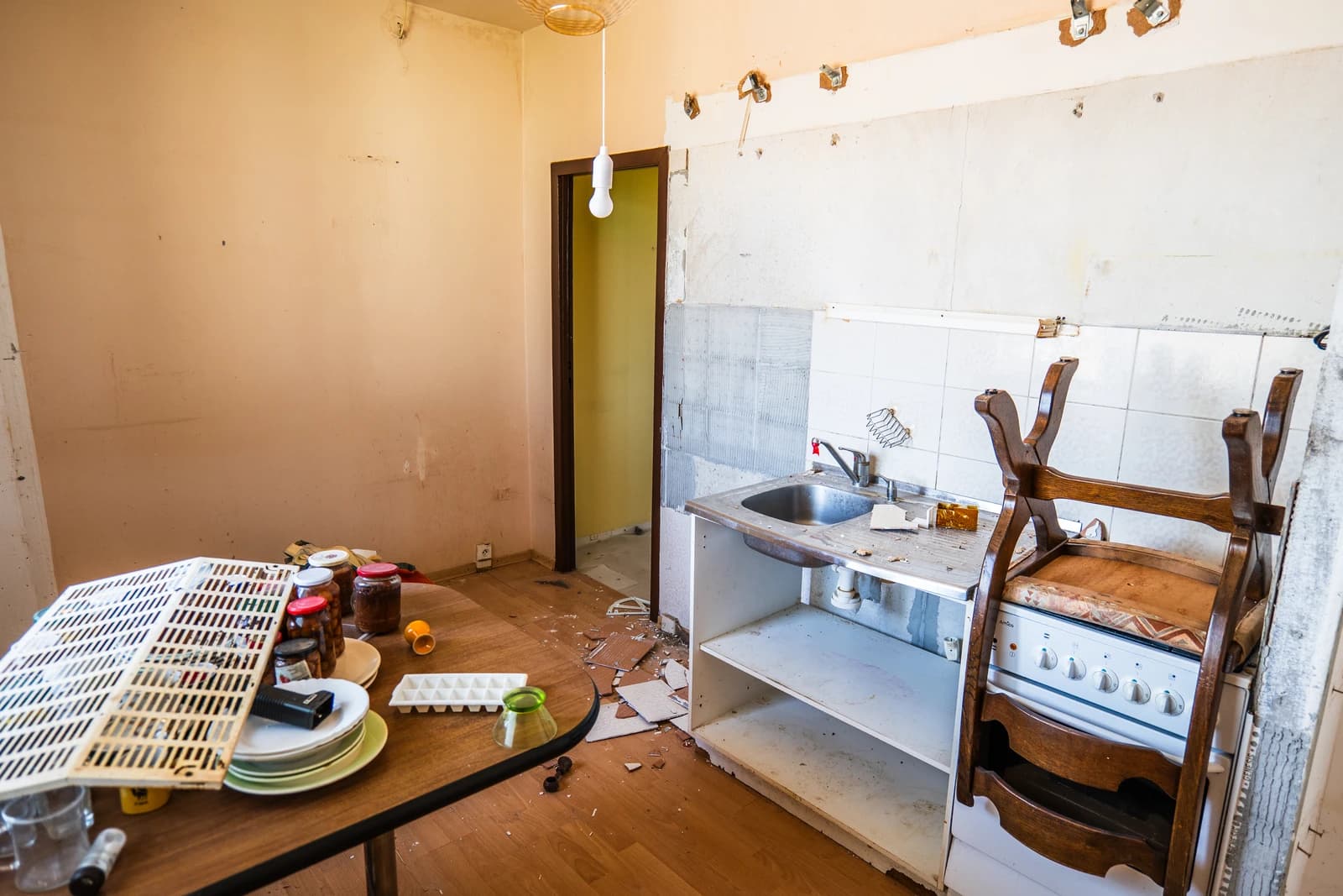 Štýlová tmavá kuchyňa s moderným osvetlením, zlatými akcentmi a elegantným jedálenským stolom.