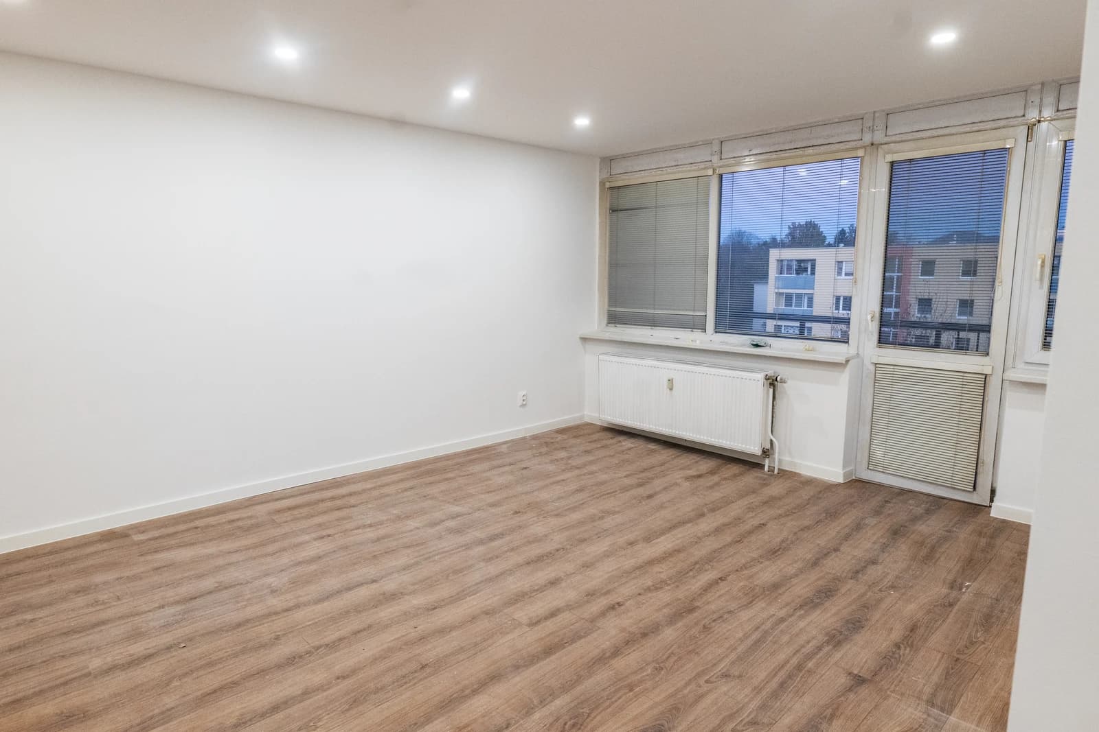 Štýlová tmavá kuchyňa s moderným osvetlením, zlatými akcentmi a elegantným jedálenským stolom.