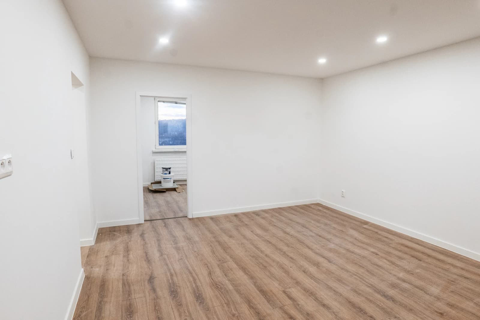 Štýlová tmavá kuchyňa s moderným osvetlením, zlatými akcentmi a elegantným jedálenským stolom.