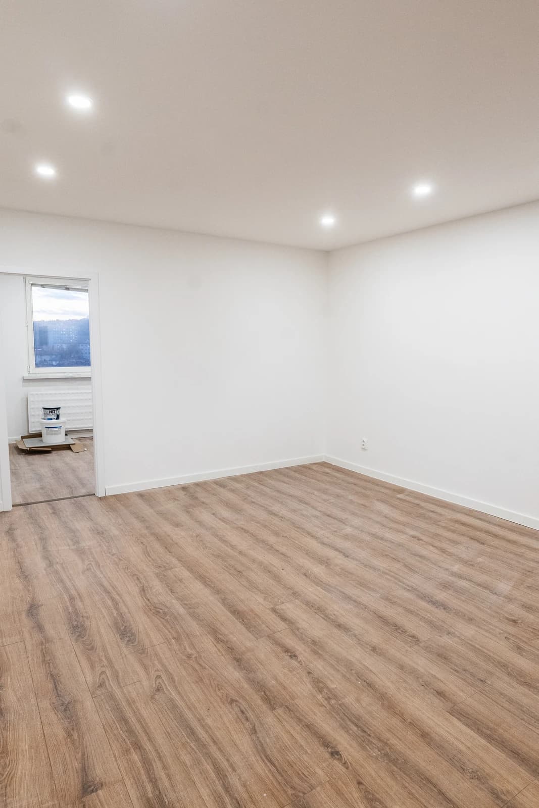 Štýlová tmavá kuchyňa s moderným osvetlením, zlatými akcentmi a elegantným jedálenským stolom.