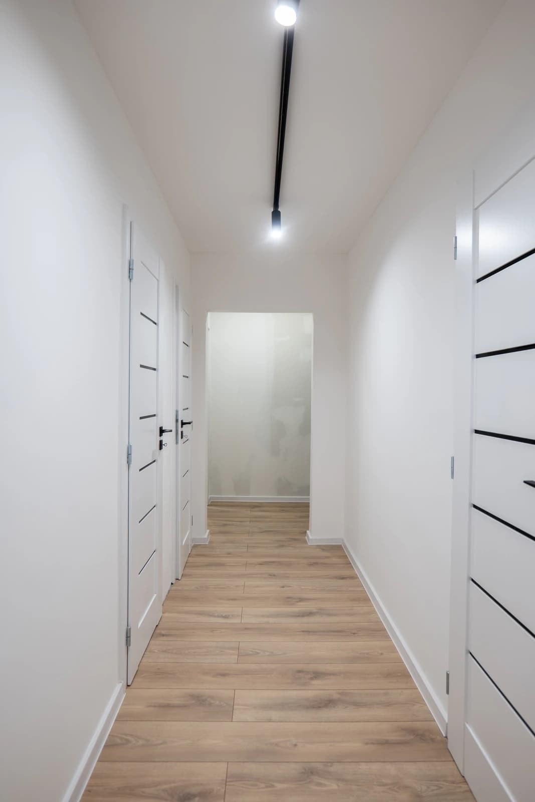 Štýlová tmavá kuchyňa s moderným osvetlením, zlatými akcentmi a elegantným jedálenským stolom.