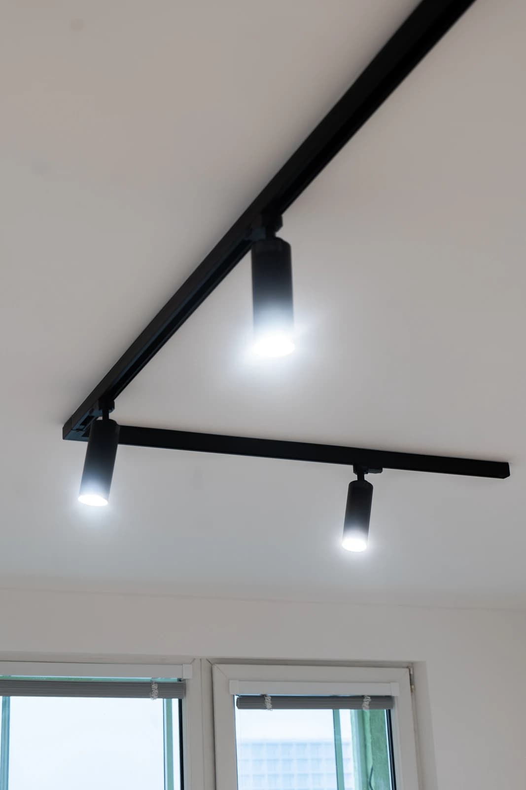 Štýlová tmavá kuchyňa s moderným osvetlením, zlatými akcentmi a elegantným jedálenským stolom.