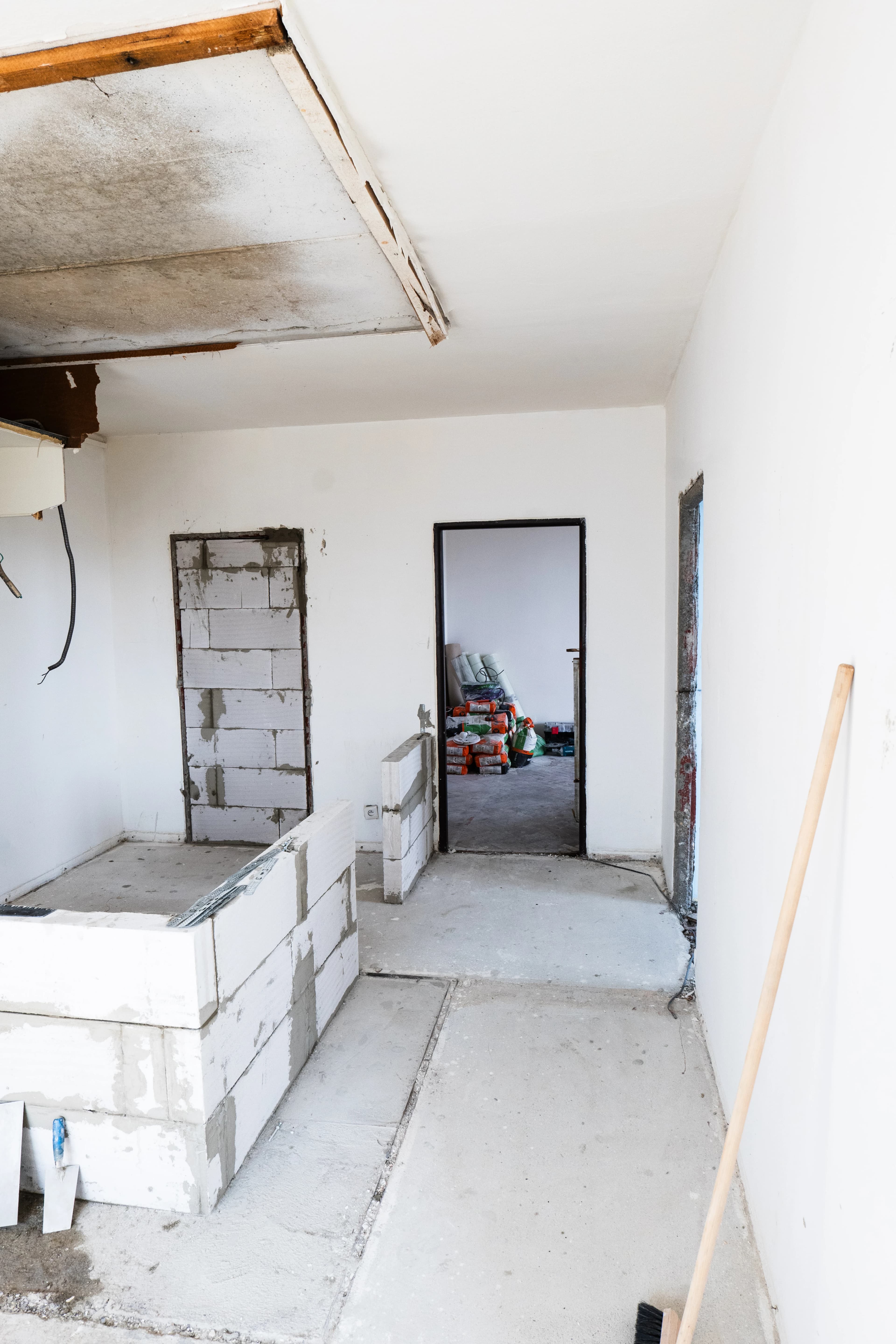 Štýlová tmavá kuchyňa s moderným osvetlením, zlatými akcentmi a elegantným jedálenským stolom.