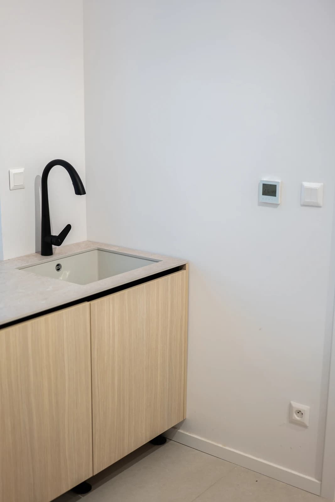 Štýlová tmavá kuchyňa s moderným osvetlením, zlatými akcentmi a elegantným jedálenským stolom.