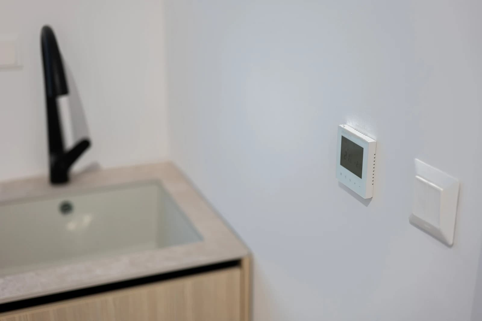 Štýlová tmavá kuchyňa s moderným osvetlením, zlatými akcentmi a elegantným jedálenským stolom.