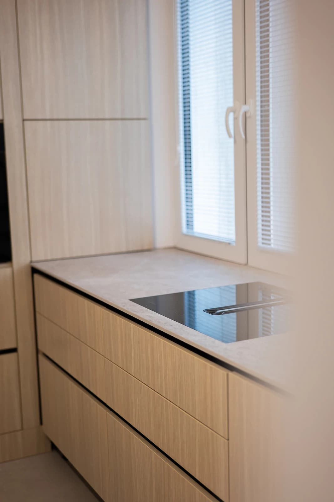 Štýlová tmavá kuchyňa s moderným osvetlením, zlatými akcentmi a elegantným jedálenským stolom.