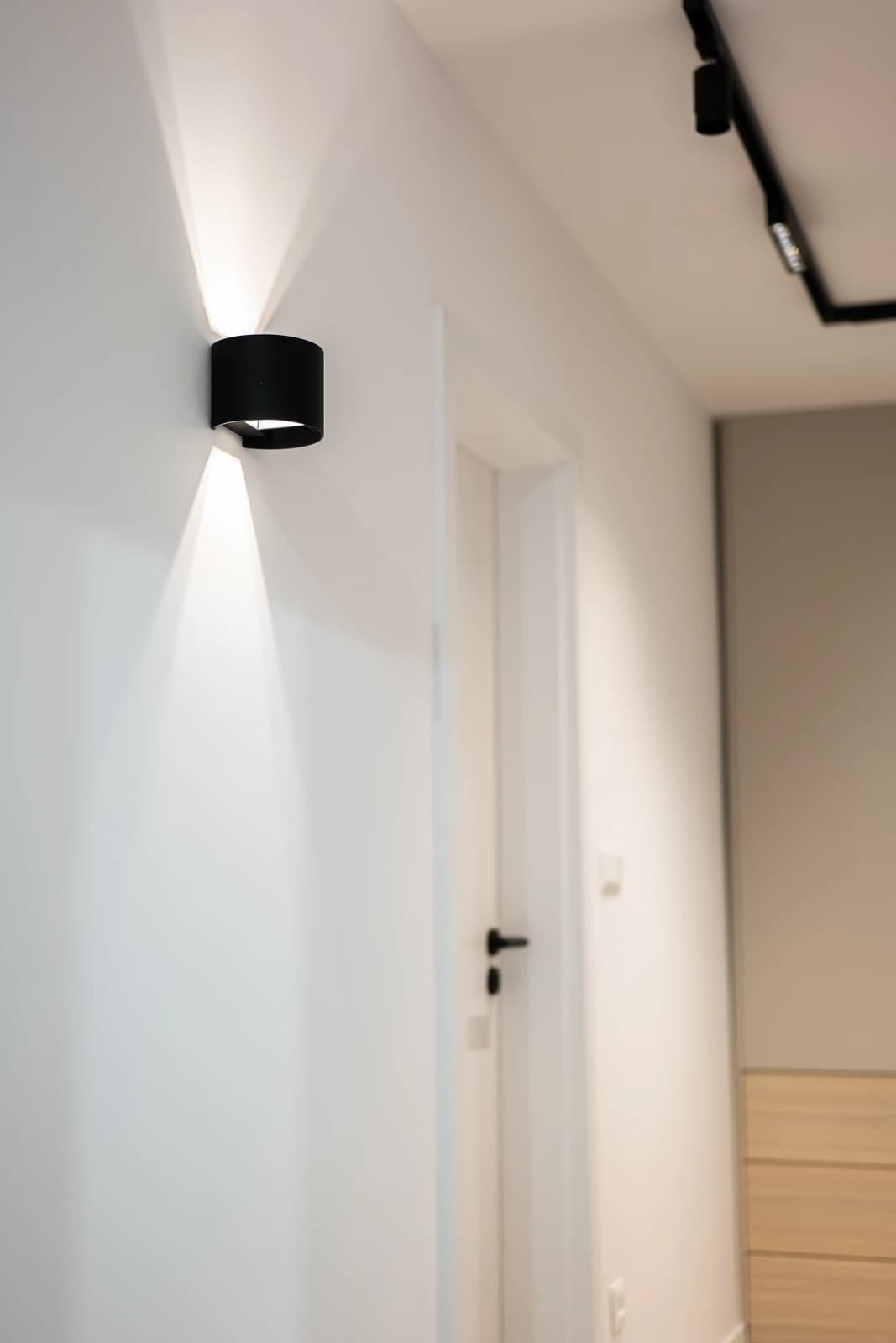 Štýlová tmavá kuchyňa s moderným osvetlením, zlatými akcentmi a elegantným jedálenským stolom.