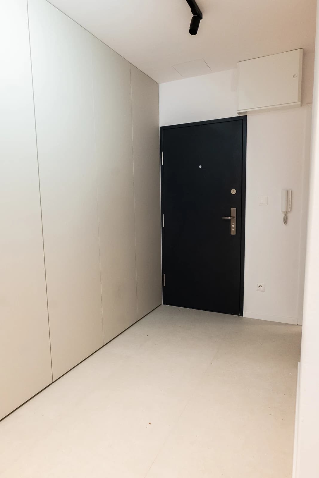 Štýlová tmavá kuchyňa s moderným osvetlením, zlatými akcentmi a elegantným jedálenským stolom.