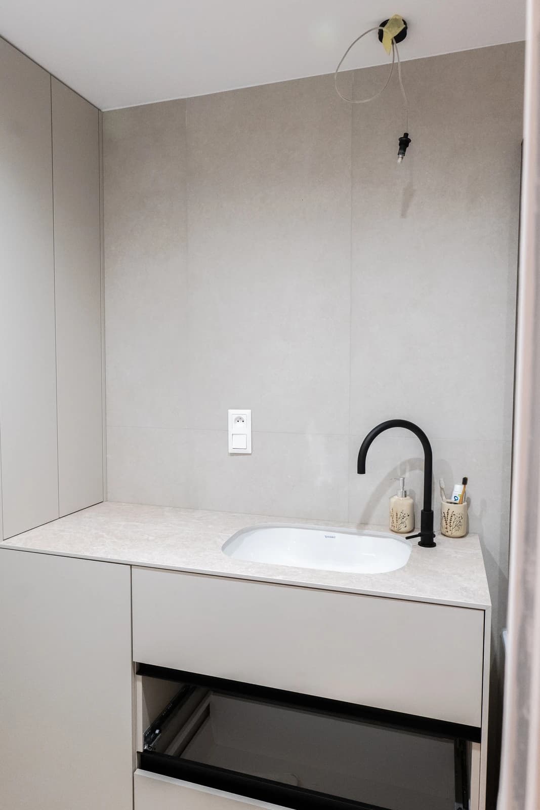 Štýlová tmavá kuchyňa s moderným osvetlením, zlatými akcentmi a elegantným jedálenským stolom.