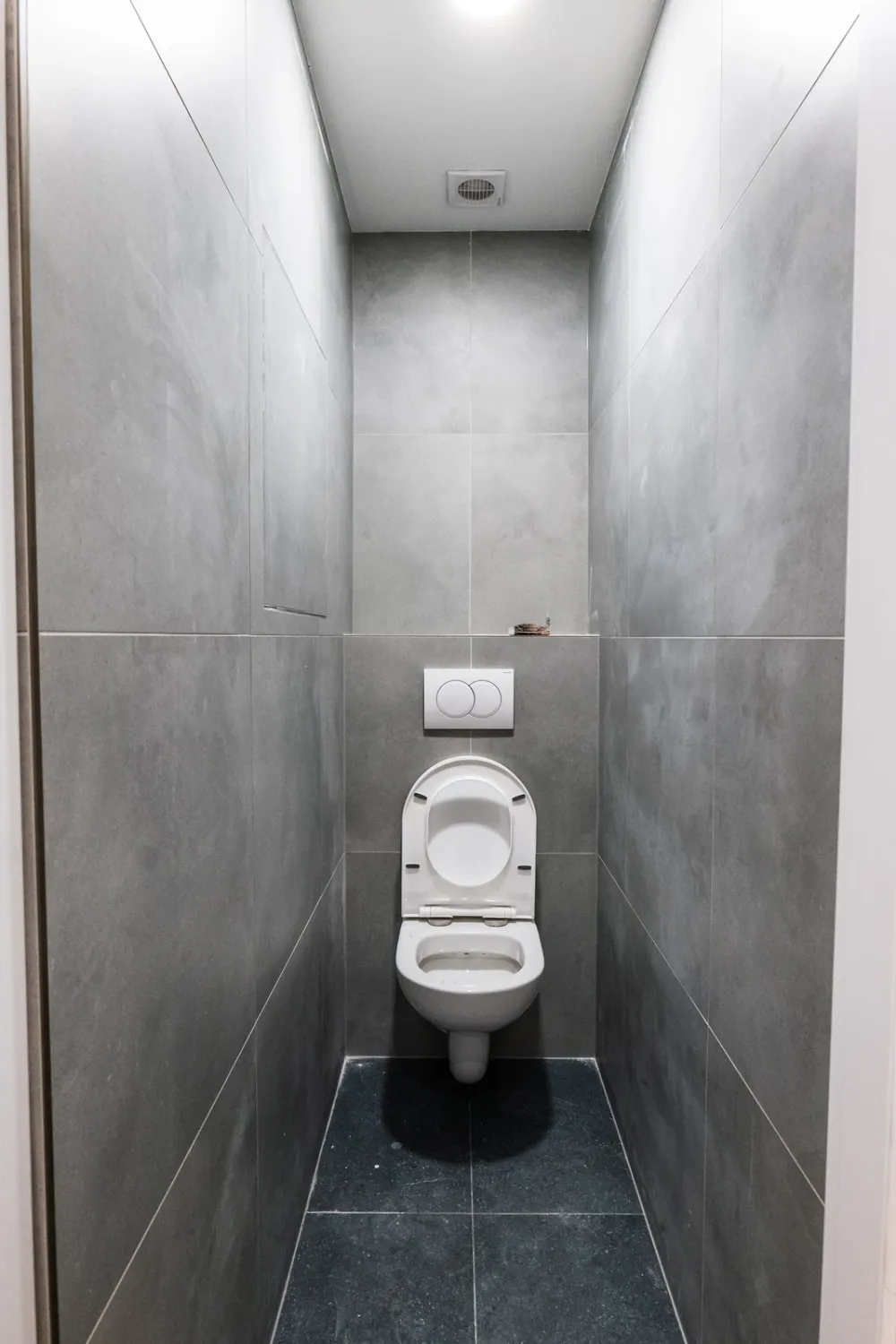 Štýlová tmavá kuchyňa s moderným osvetlením, zlatými akcentmi a elegantným jedálenským stolom.